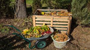 Garden waste including leaves and branches in a wheelbarrow and wooden bin